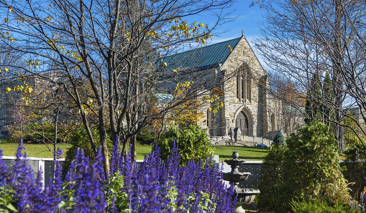 The Beechwood Cemetery mausoleum, gothic chapel, stone statues on the peaks of the roofs and purple spring flowers