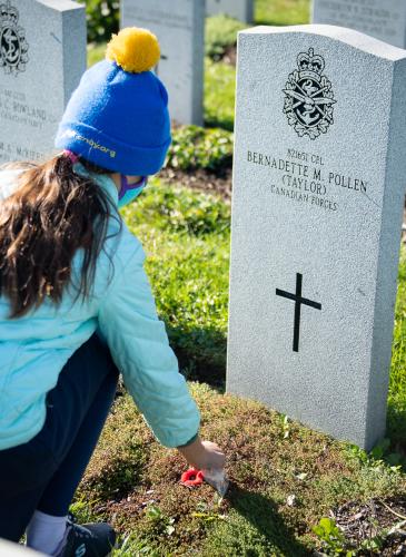 Child placing a poppy on headstone
